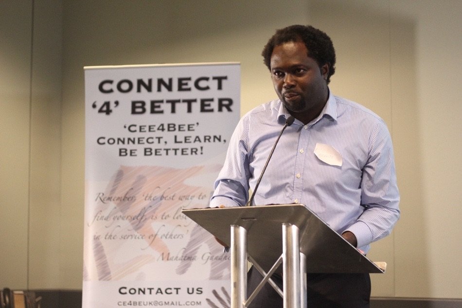 Ayo Akande speaking beside a Connect4Better banner